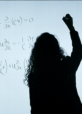 Woman writes maths equation on a board.
