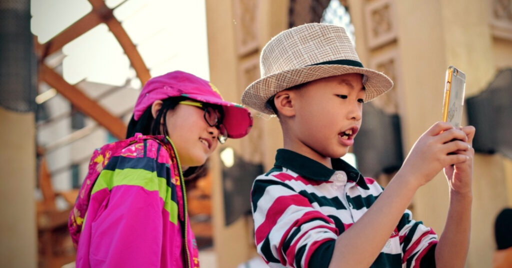 Two younger children use a smartphone 