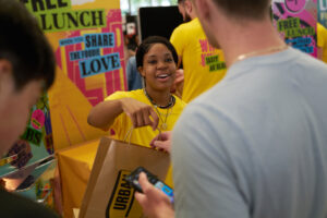 An ambassador hands a goodie bag to a student at a Freshers fair