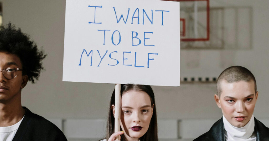 Girl holds a sign bearing the slogan "I want to be myself" 