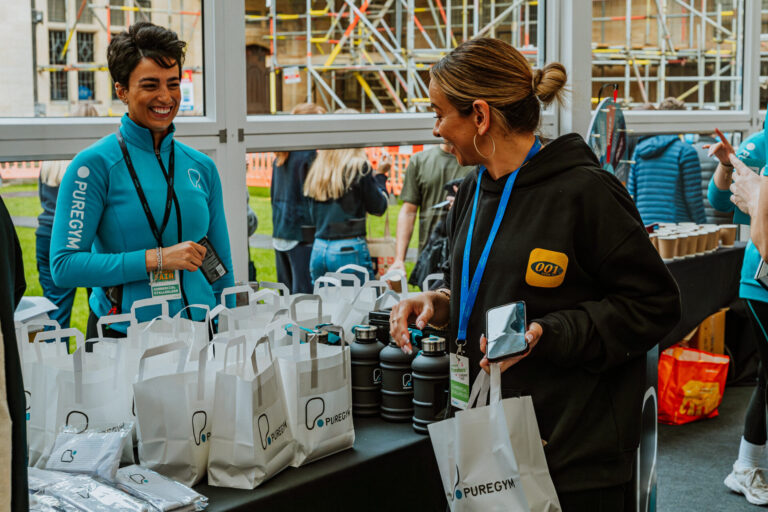 PureGym staff member at a freshers fall stall, talking to students.