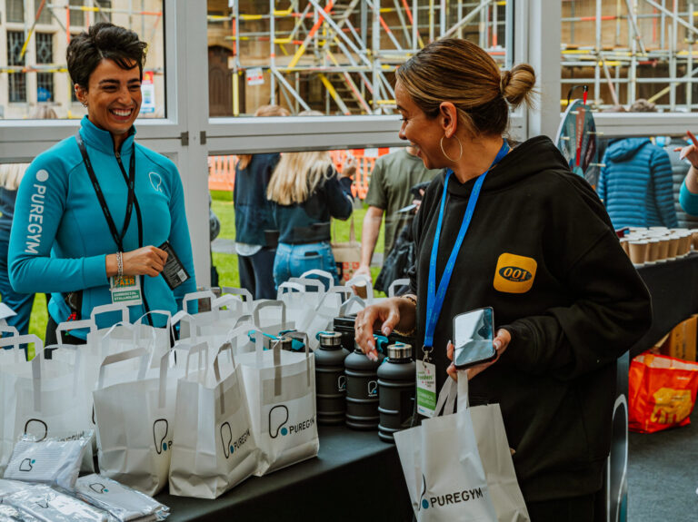 PureGym staff member at a freshers fall stall, talking to students.