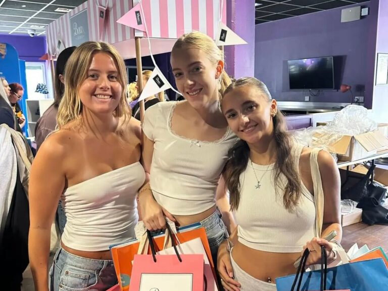 Three students standing in front of Boux Avenue Freshers stall.